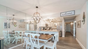 A modern kitchen with white cabinets, a wooden island, and a 'welcome' sign. - Bethys Beachy Beauty Regency Towers! (Panama City Beach)