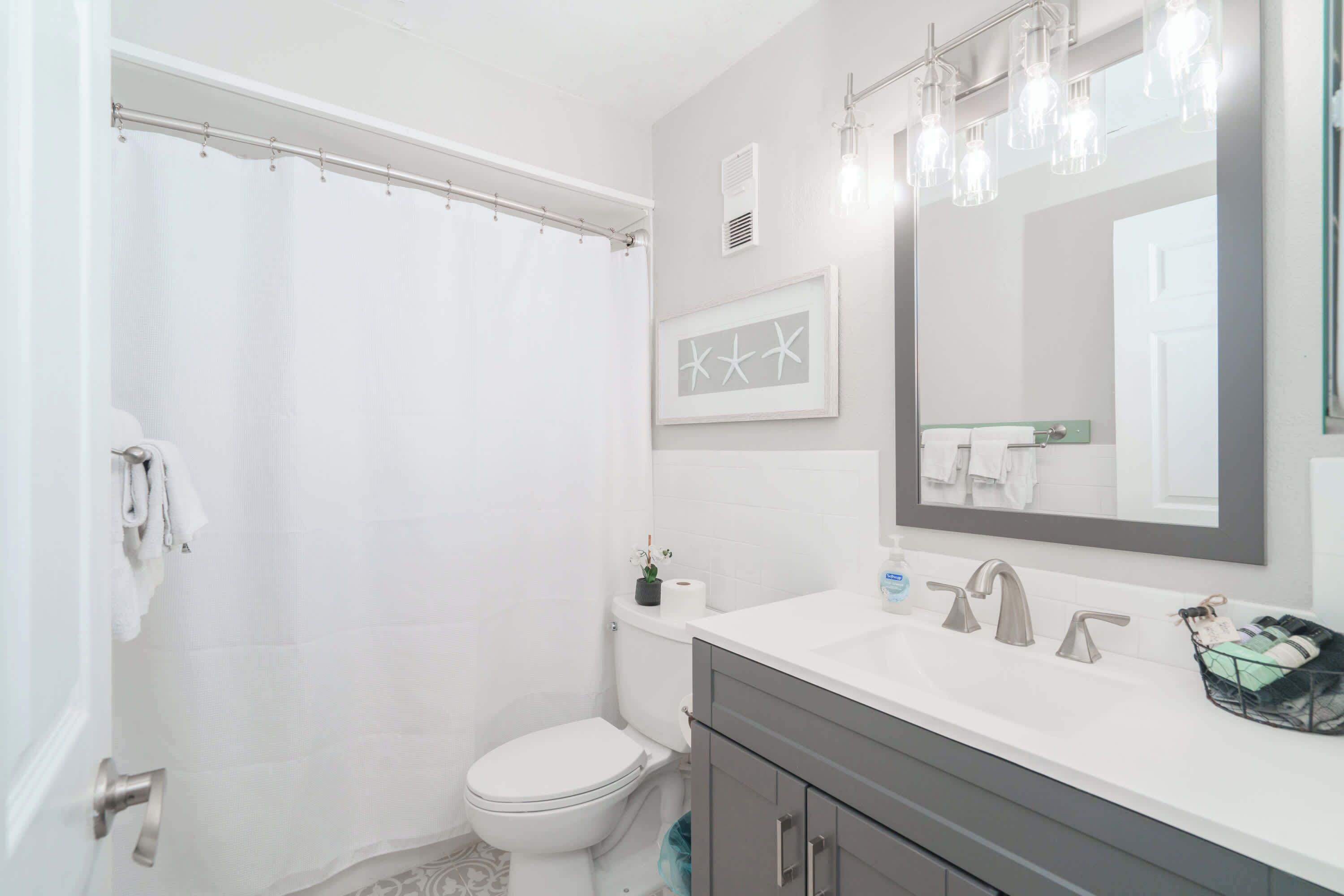 A bathroom with a shower, toilet, sink, and vanity.