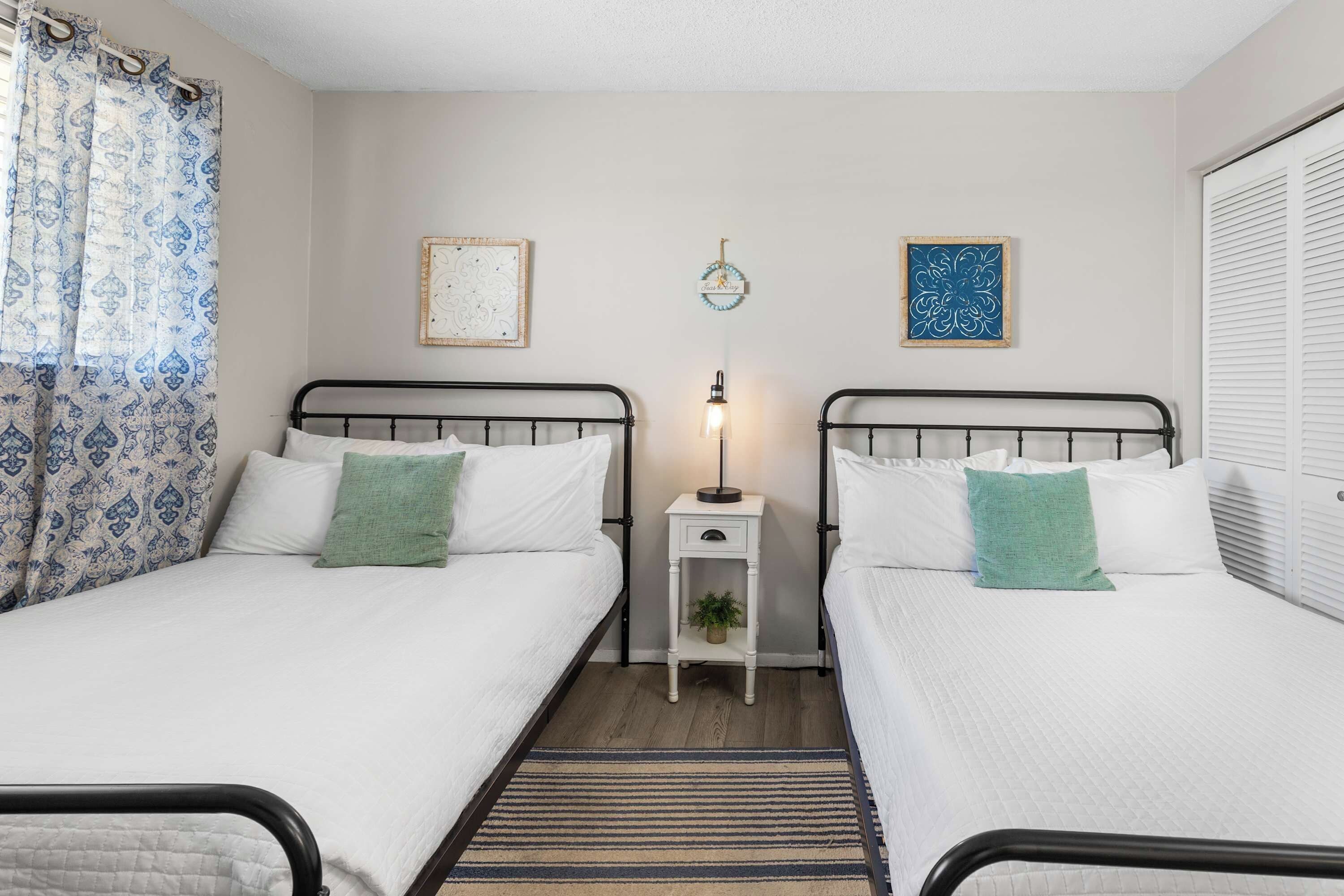 A twin room with two beds, a nightstand, a lamp, and decorative wall art.