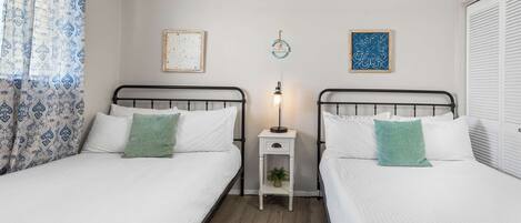 A twin room with two beds, a nightstand, a lamp, and decorative wall art.
