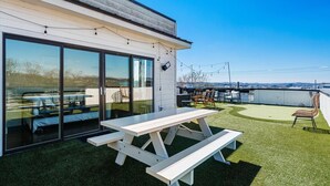 Una terraza en la azotea con una mesa de picnic, sillas y vistas de la ciudad.