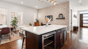 Una cocina moderna con una isla grande, armarios de madera y una pared decorativa de ladrillo.