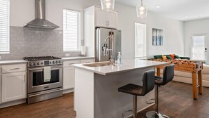 A modern kitchen with a central island, stainless steel appliances, and pendant lighting.