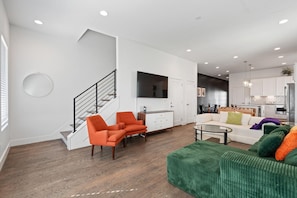 A modern living room with a staircase, a dining area, and a kitchen. - Bar, Grill & Firepit! Sleeps 16! 8min to Broadway! (Nashville)