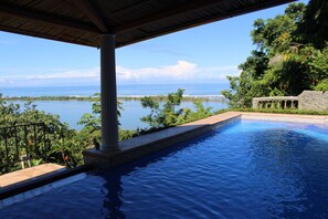 A swimming pool with a view of the ocean and a covered area with a column. - El Paraiso Azul (Ciudad Cortés)
