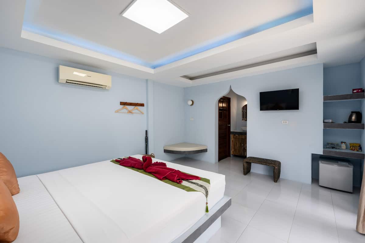Een moderne hotelkamer met een groot bed, een klein bureau, een televisie en een inbouwkbank.