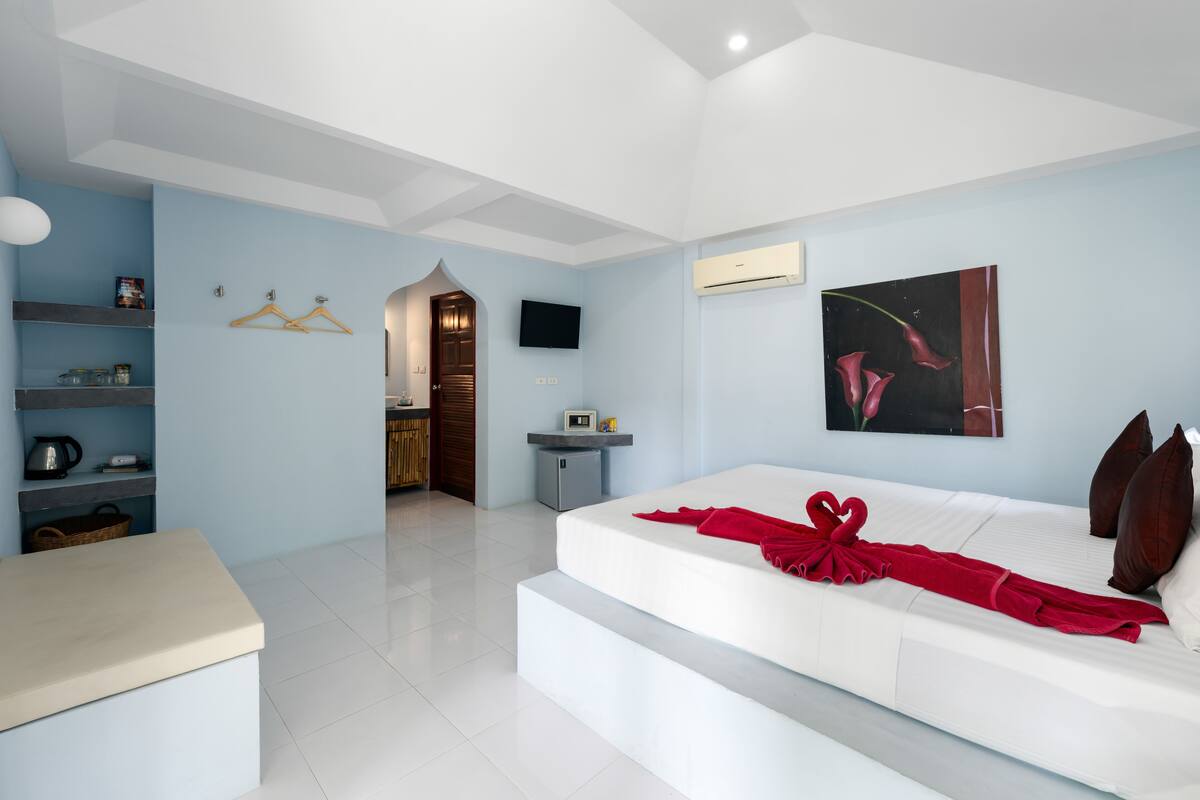 Een moderne hotelkamer met een groot bed, een flatscreen televisie, een schilderij en een kitchenette.