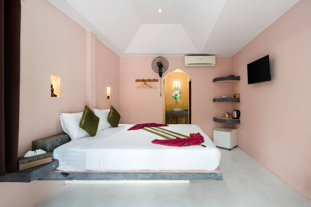Een moderne slaapkamer met een bed, nachtkastje en een kleine kitchenette.