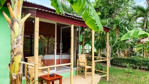 A bamboo-framed outdoor seating area with a table and chairs, a covered entrance, and lush greenery surrounding the structure. - Avocado (Koh Samui)
