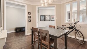 A dining area with a large table, chairs, and a bicycle. - Warm Suburban 3BR Townhome near DT (Austin)