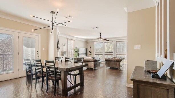 A spacious living room with a dining area, large windows, and a ceiling fan. - Warm Suburban 3BR Townhome near DT (Austin)