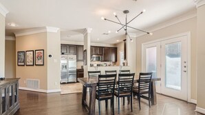 A spacious kitchen with modern appliances, a dining area with a wooden table and chairs, and a large window providing natural light. - Warm Suburban 3BR Townhome near DT (Austin)