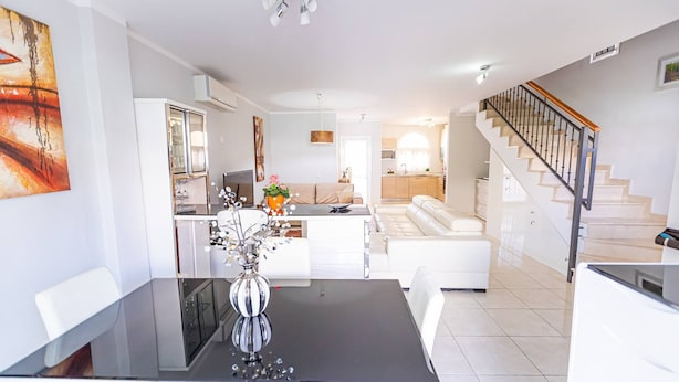 A modern living room with a dining table, white sofas, and a staircase. - Townhouse in Palm-Mar  (Arona)