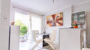 A modern kitchen with a dining area, a refrigerator, a table with chairs, and a cabinet with glassware. - Townhouse in Palm-Mar  (Arona)