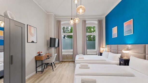Une chambre d’hôtel équipée d’un lit, d’un bureau, d’une télévision et offrant une vue sur l’extérieur.