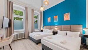 Une chambre d’hôtel avec deux lits, un bureau, une chaise et un téléviseur.