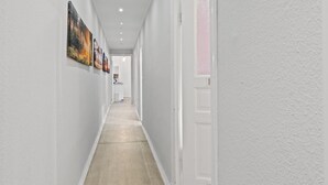 Un couloir aux murs blancs, doté d’un plancher en bois et d’une porte en verre dépoli.