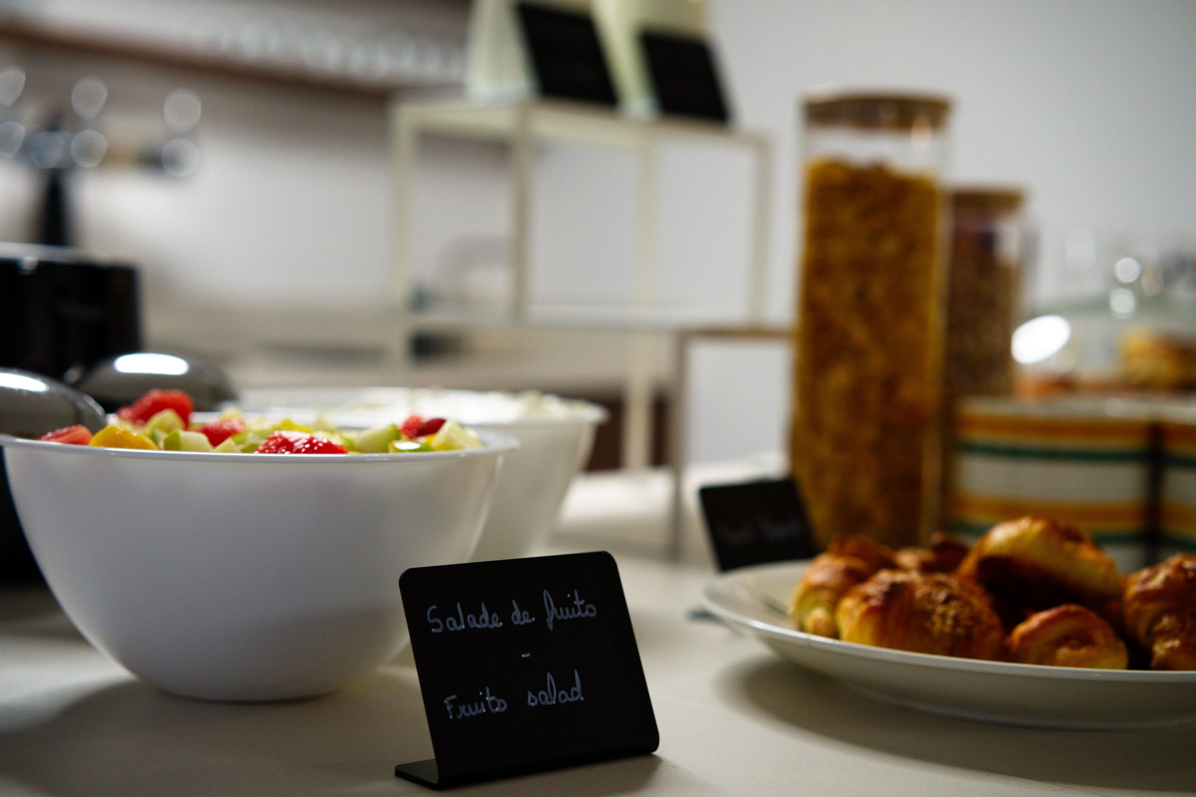 Un bufé de desayuno con un cartel que indica opción de ensalada de frutas.