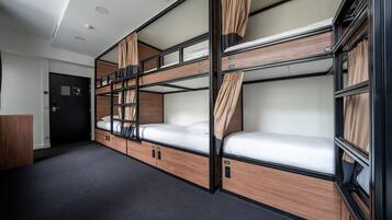 Una habitación de hotel pequeña con literas, un escritorio y un armario.