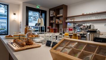 Un comptoir de café avec du pain, du matériel pour préparer le café et une vitrine remplie de pâtisseries.