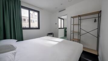 Ein Schlafzimmer mit Bett, Stuhl, Kleiderschrank und einem Fenster mit Vorhängen.