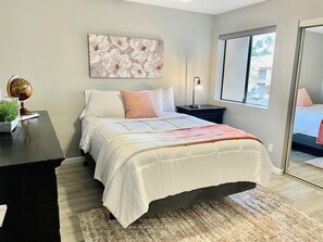 A modern bedroom with a bed, a nightstand, a globe, and a window with a view.