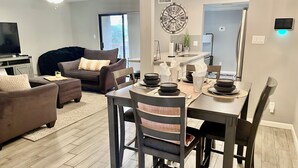 A modern living room with a sofa, a dining table set with plates and bowls, a clock on the wall, and a ceiling fan. - AZ Peaceful Retreat in Scottsdale (Scottsdale)