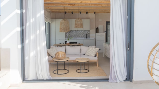 Un intérieur moderne avec un canapé, deux petites tables rondes et une cuisine en arrière-plan.