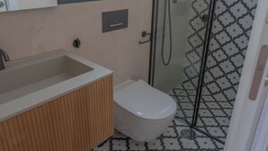 Une salle de bain comprenant des toilettes, un lavabo et un espace douche.