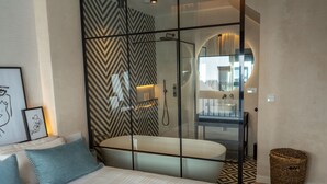 Une chambre à coucher moderne avec un grand lit, une douche en verre et une vue sur la salle de bain.
