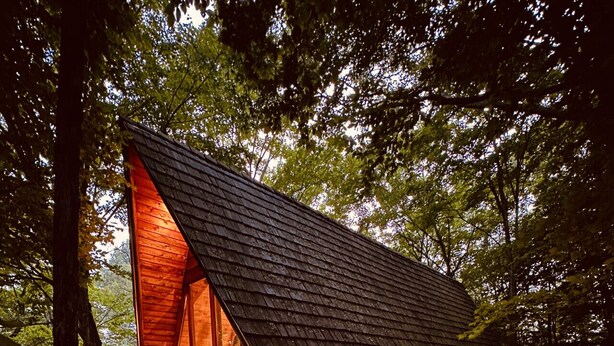 Een houten chalet met een schuin dak, een jacuzzi en een terras.