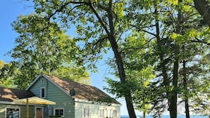 A house with a patio, outdoor seating, and a view of the water. - Lakefront Getaway | Hot Tub, Fire Pit & Sunsets (Selkirk)