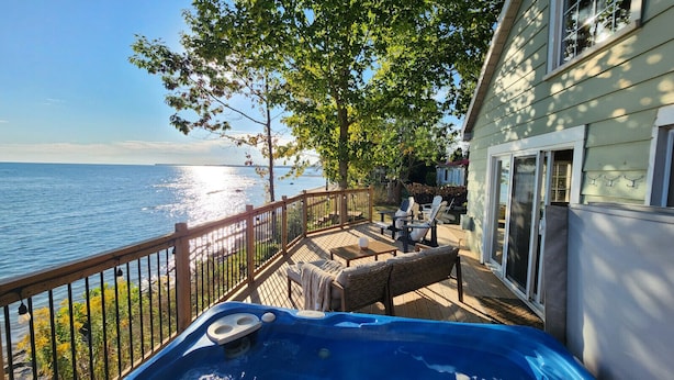 A deck with outdoor furniture, a hot tub, and a view of the water. - Lakefront Getaway | Hot Tub, Fire Pit & Sunsets (Selkirk)