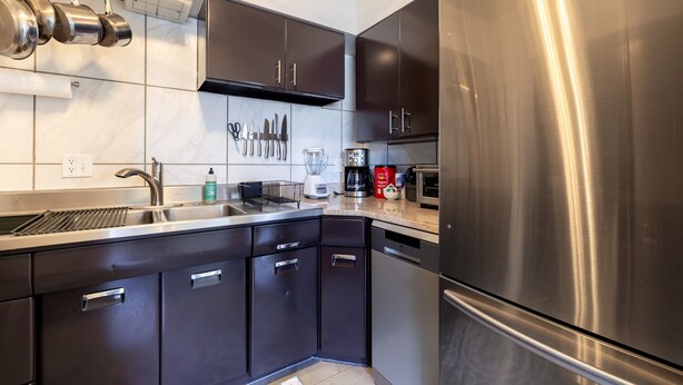 Una cocina moderna con electrodomésticos de acero inoxidable, armarios oscuros y salpicadero de azulejos.