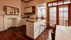 A kitchen with a central island, wooden flooring, white cabinetry, and a view through large windows.
