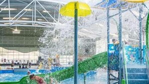 An indoor swimming pool with a water slide and a covered roof structure.