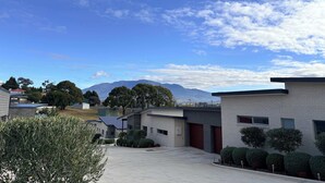 Un barrio residencial con casas modernas, cielo despejado y montañas al fondo.