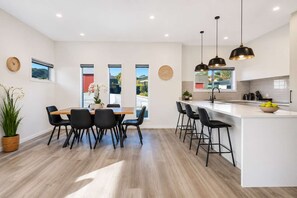 A modern kitchen with a central island, black bar stools, and pendant lighting.
