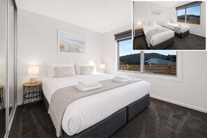 A hotel room with a large bed, two bedside tables, a window with a view, and a painting on the wall.