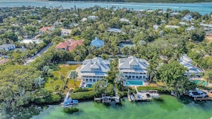 Vue aérienne d’une zone résidentielle côtière, avec des maisons, une marina et une vue dégagée sur l’océan.