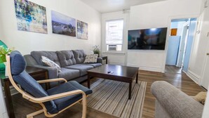 Una sala de estar moderna con un sofá gris, una mesa de centro de madera y un televisor de pantalla plana montado en la pared.