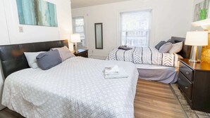 Habitación de hotel con dos camas, un espejo grande y vistas a la ciudad.