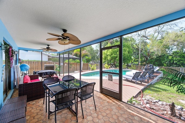 A covered patio area with a pool, outdoor furniture, and ceiling fans.