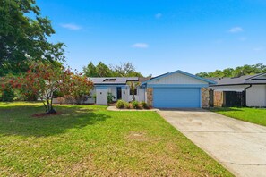 A two-story residential building with a garage, a driveway, and a well-maintained lawn.