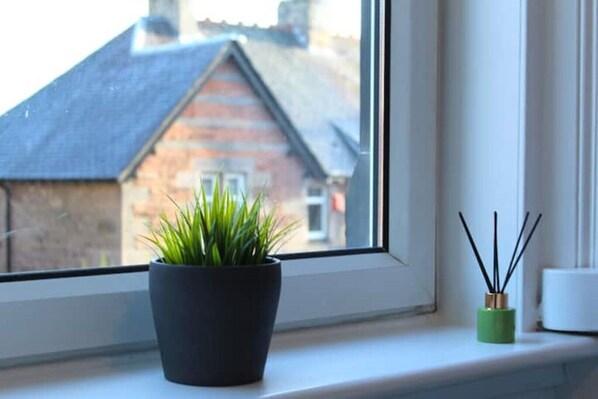 A window with a potted plant and reed diffuser on a windowsill. - Modern Stylish Apartment with central access (Perth)