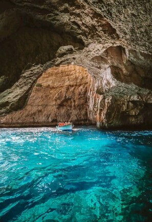 Un bote en una cueva azul cristalina con paredes rocosas.