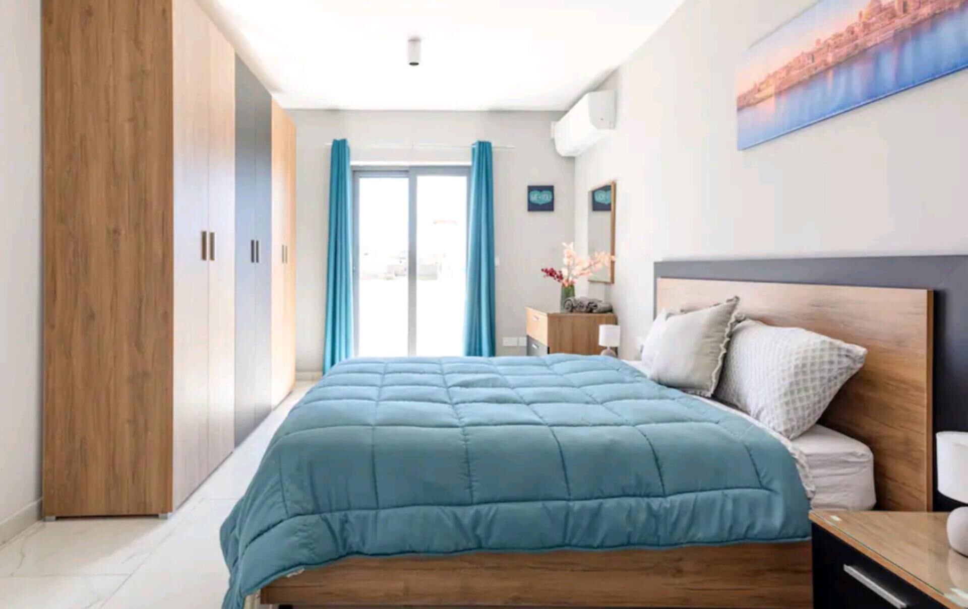 A bedroom with a bed, wooden wardrobe, and a nightstand.