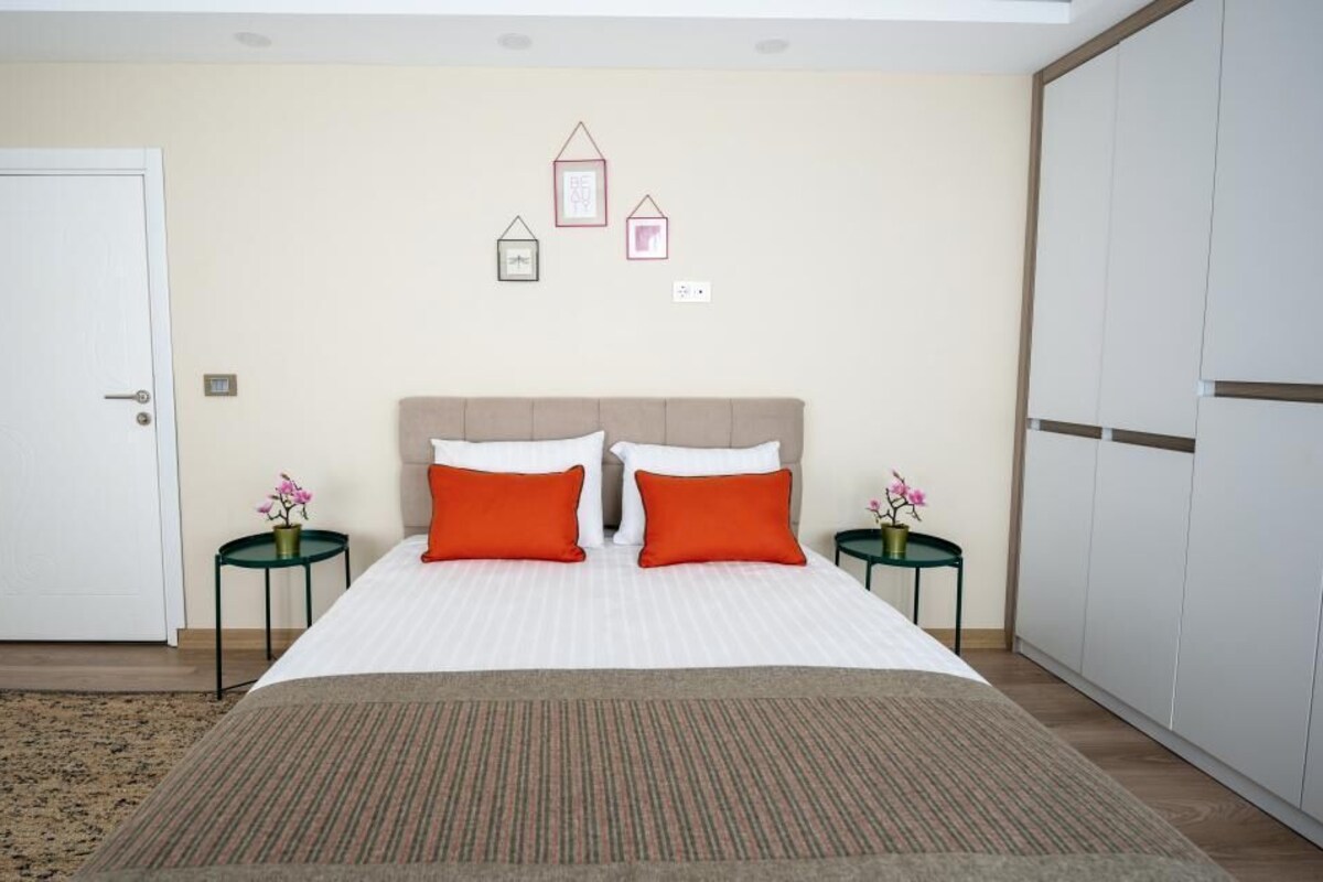 Un dormitorio con cama, dos mesitas de noche, una puerta y un armario.
