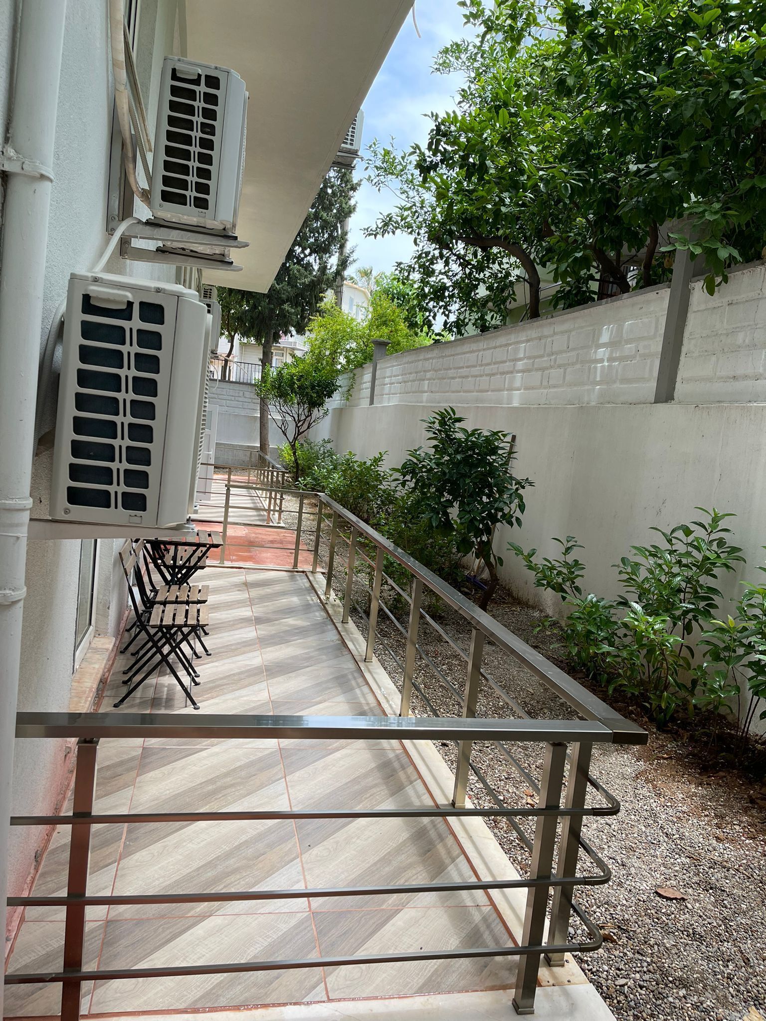 A corridor with a tiled floor, metal railings, and outdoor seating.