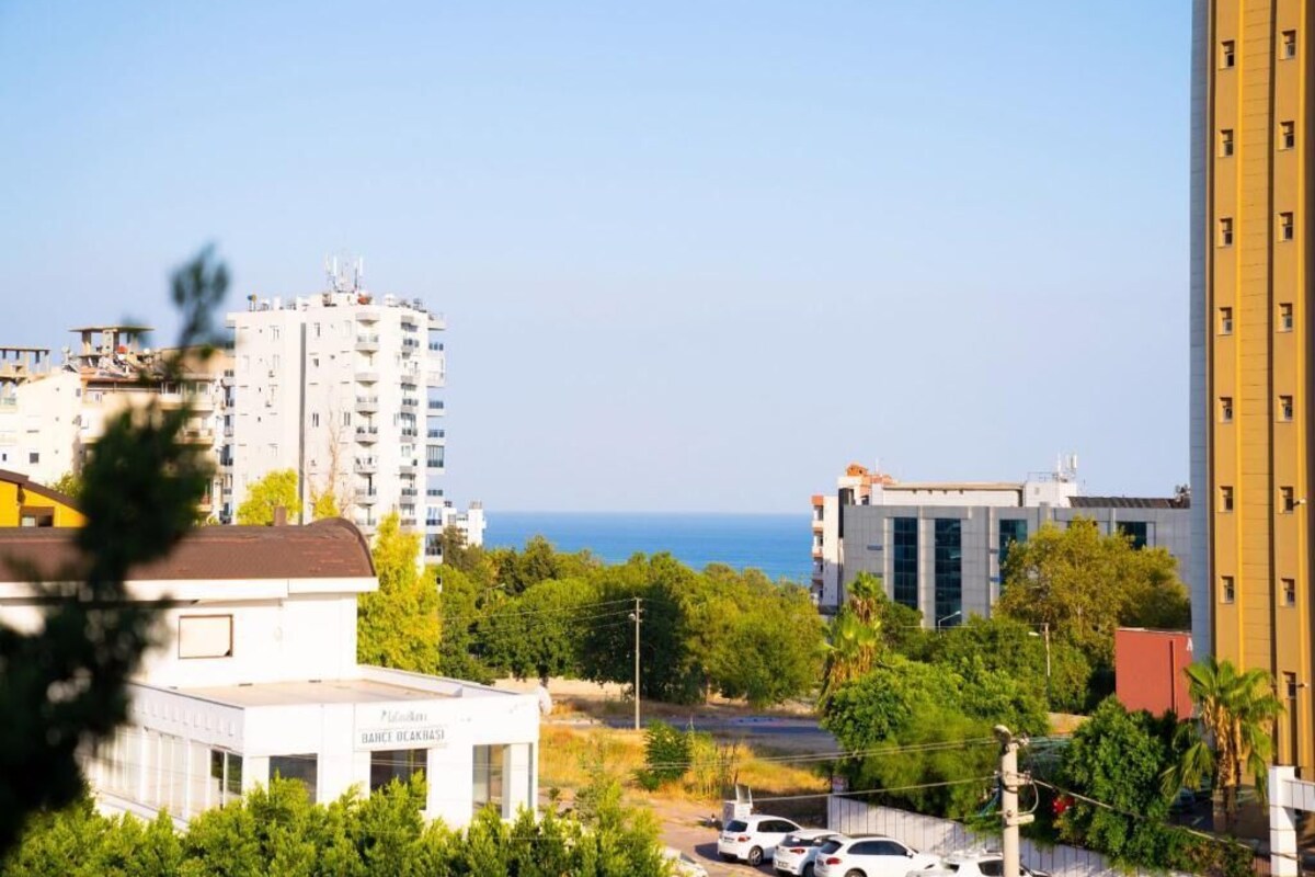 Un rascacielos con vista al mar, rodeado de vegetación y otros edificios.